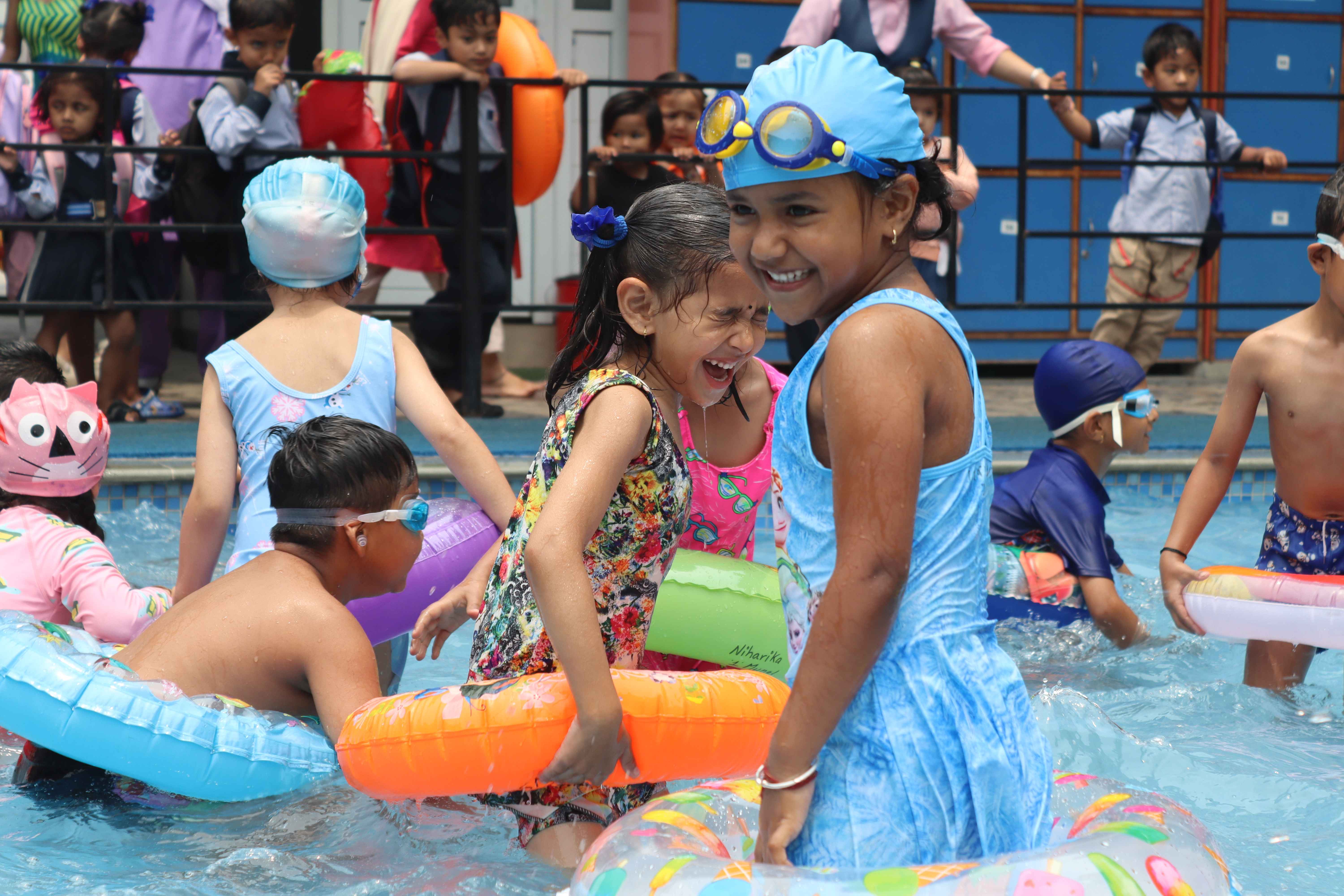 small students are playing on swimming pool